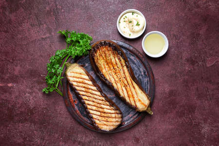 Tasty grilled eggplant with sauces on color backgroundの写真素材