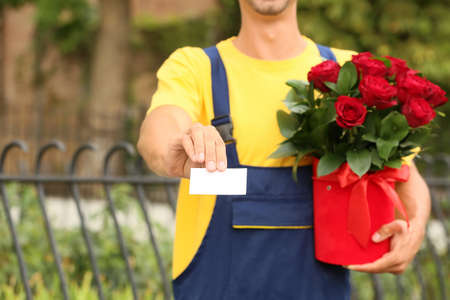 Delivery man with beautiful flowers and business card outdoorsの写真素材