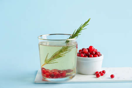 Glass of champagne cocktail with cranberry and rosemary on color backgroundの写真素材