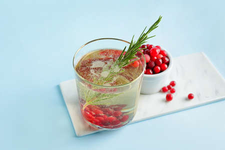 Glass of champagne cocktail with cranberry and rosemary on color backgroundの写真素材
