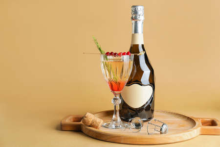 Tray with bottle of champagne and cocktail in glass on color backgroundの写真素材