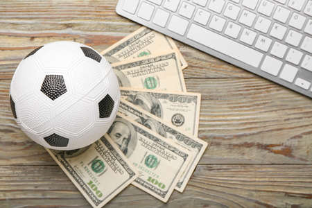 Money, soccer ball and keyboard on wooden backgroundの写真素材