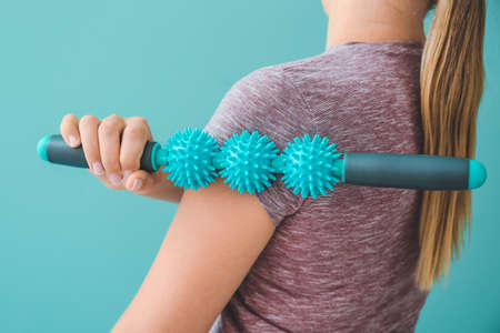 Sportswoman massaging herself with body roller on color backgroundの写真素材
