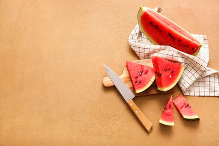 Wooden board with slices of ripe watermelon on color background