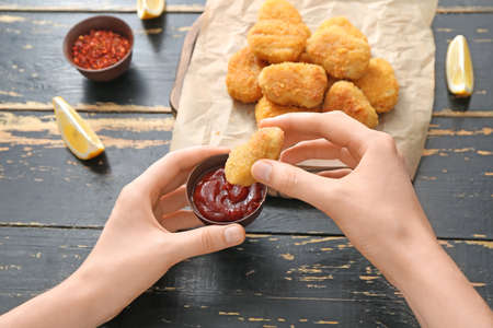 Woman eating tasty nuggets with ketchup on wooden backgroundの写真素材