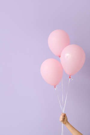 Human hand with air balloons on color backgroundの写真素材
