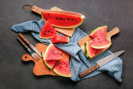 Wooden boards with slices of ripe watermelon on dark backgroundの写真素材