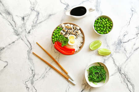 Bowl with tasty rice, chicken and vegetables on light backgroundの写真素材