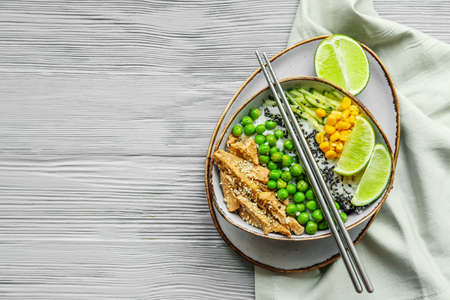 Bowl with tasty rice, chicken and vegetables on wooden backgroundの写真素材