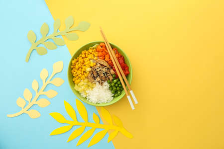 Bowl with tasty rice, chicken and vegetables on color backgroundの写真素材
