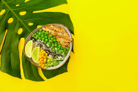Bowl with tasty rice, chicken and vegetables on color background