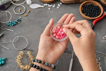 Female jewelry designer with beads at tableの写真素材