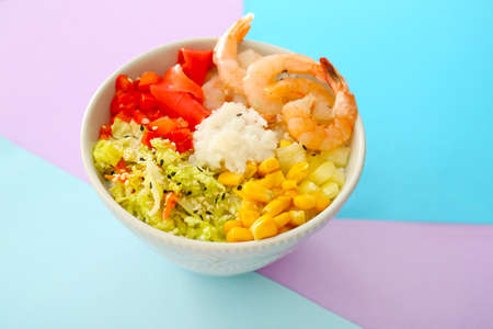 Bowl with tasty rice, shrimps and vegetables on color backgroundの写真素材