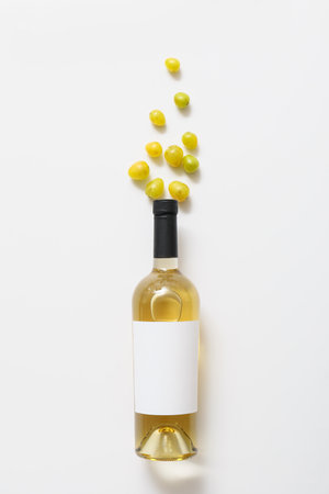 Bottle of wine with blank label and grapes on white backgroundの写真素材