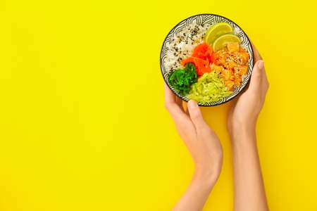 Woman with rice poke bowl on color background