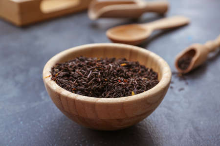 Dry black tea leaves in bowl on dark backgroundの写真素材