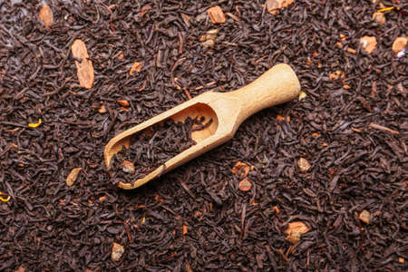 Dry black tea leaves with scoop as backgroundの写真素材