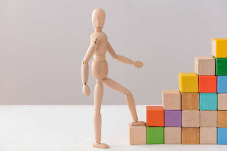 Stacked blocks with human figure on light backgroundの写真素材