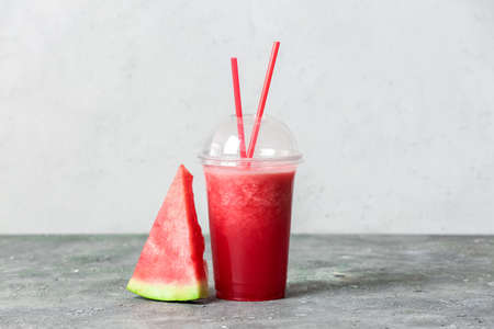 Plastic cup with fresh watermelon juice on light backgroundの写真素材