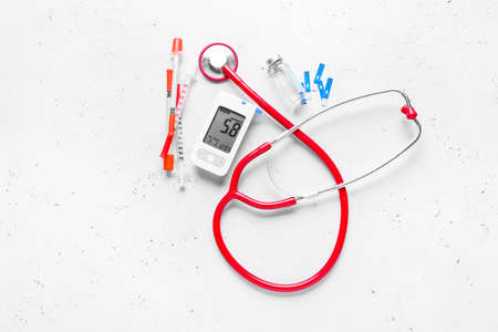 Glucometer, stethoscope, insulin and syringes on white background. Diabetes concept
