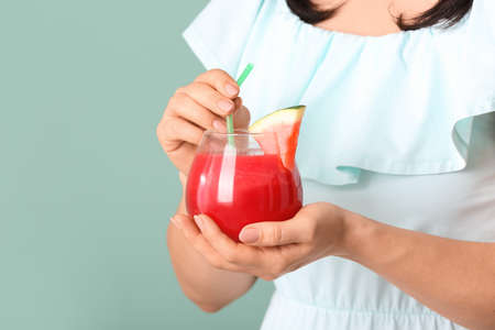 Woman with glass of fresh watermelon juice on color backgroundの写真素材