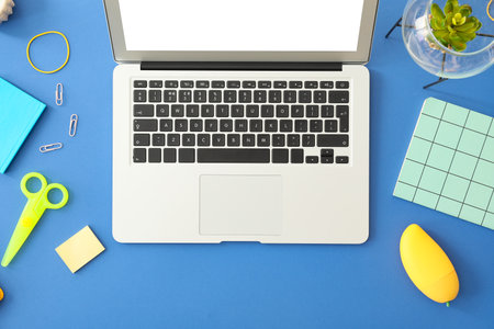 Modern laptop with stationery on color backgroundの写真素材