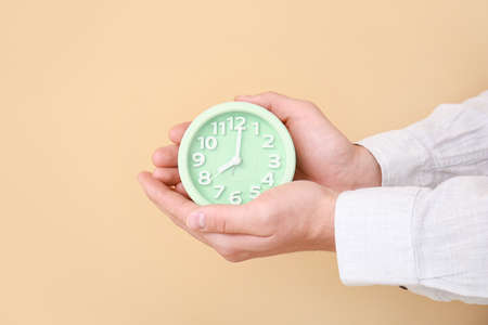 Male hands with alarm clock on color backgroundの写真素材