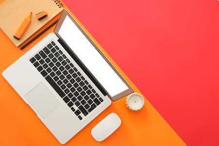 Modern laptop with stationery on color backgroundの写真素材