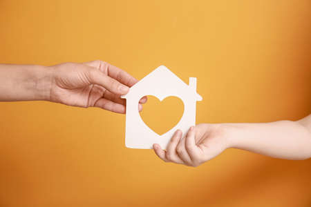 Hands of family with figure of house on color backgroundの写真素材