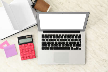 Modern laptop with stationery and cup of coffee on white backgroundの写真素材