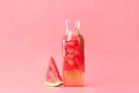 Bottle of cold watermelon lemonade on color background