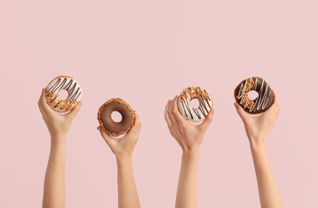 Hands with tasty donuts on color backgroundの写真素材