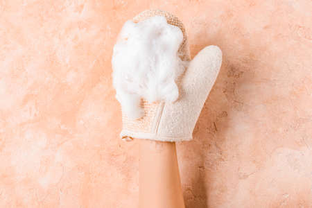 Female hand with massage glove on color background