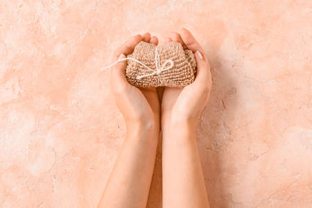 Female hands with loofah on color backgroundの写真素材