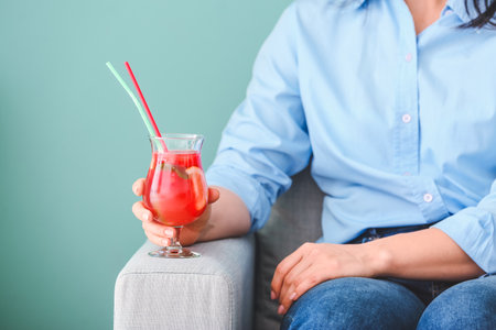 Woman holding glass of cold watermelon lemonade on color backgroundの写真素材