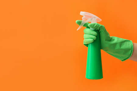 Hand in rubber glove with water sprayer on color backgroundの写真素材