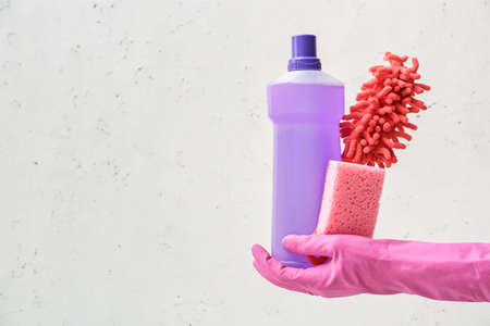 Hand in rubber glove with cleaning supplies on light backgroundの写真素材