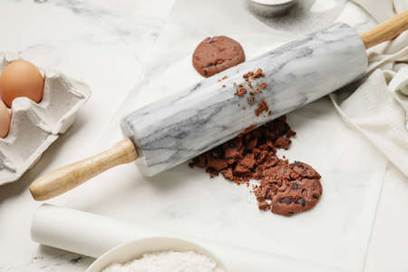 Cookies and rolling pin on light background