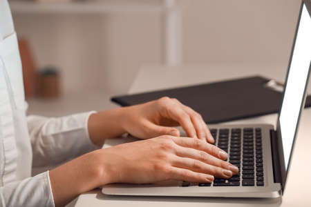 Woman working on laptop in evening, closeup