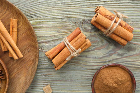 Composition with cinnamon sticks and powder on wooden background