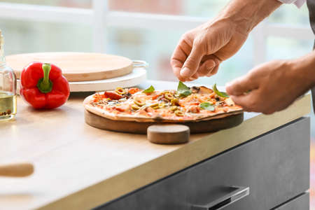 Mature male chef cooking tasty pizza in kitchen, closeup