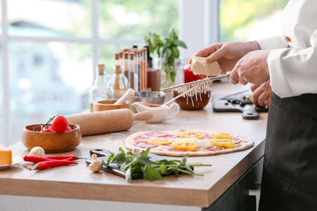 Chef making tasty pizza in kitchenの写真素材