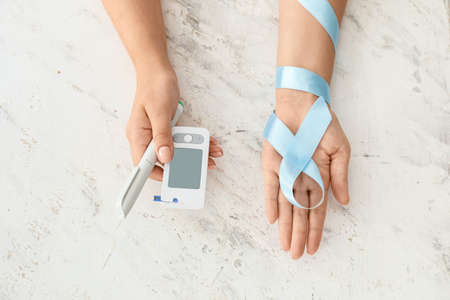 Female hands with awareness ribbon, glucometer and syringe on white background. Diabetes conceptの写真素材