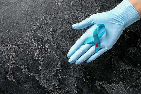 Hand of doctor with awareness ribbon on dark background. Diabetes conceptの写真素材