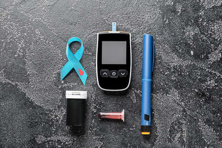 Awareness ribbon with glucometer, blood sample and syringe on dark background. Diabetes conceptの写真素材
