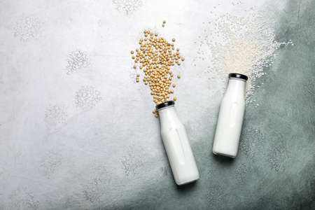 Bottles of different vegan milk on color background
