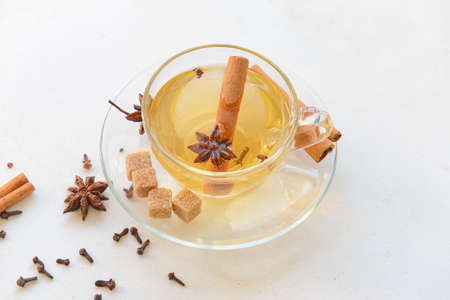 Tasty drink with cinnamon, anise and cloves in cup on light backgroundの写真素材