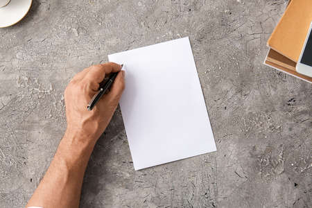 Male hand and blank paper sheet on gray backgroundの写真素材