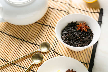 Teapot and bowl with dry black tea on light backgroundの写真素材