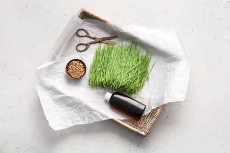 Fresh wheatgrass, seeds in bowl and bottle on light backgroundの写真素材